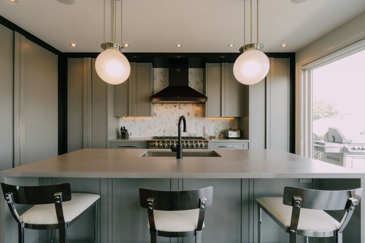 Tijdloze keuken met kaderdeuren in zachtgroen en een eiland met krukken