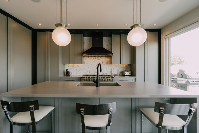 Tijdloze keuken met kaderdeuren in zachtgroen en een groot eiland met krukken